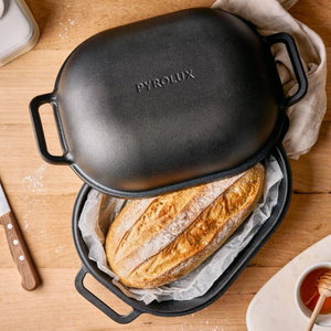 Pyrolux Pyrocast Bake & Roast Set with a loaf of bread inside on a wooden table.