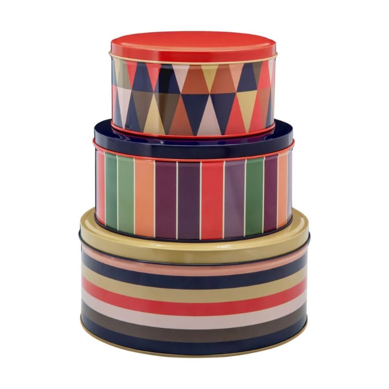 Stack of colourful cylindrical tins with stripes and geometric patterns on a white background – Remember Klara Round Storage Tins.