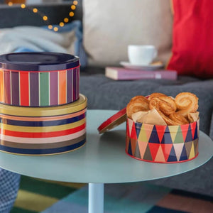 Remember Klara Round Storage Tins on a table, one open with pastries inside.