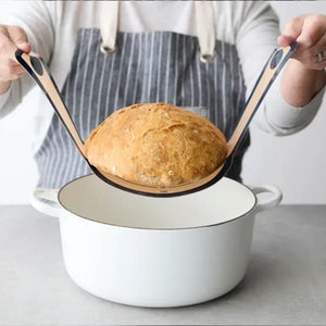 Person using the RSVP Silicone Bread Sling to lift bread out of a dutch oven.
