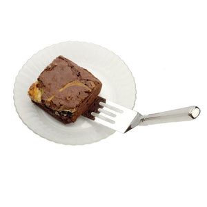 RSVP Stainless Steel Brownie Spatula holding a piece of brownie on a white plate on a white background.