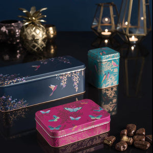 Three Sara Miller decorative tins with floral and butterfly designs on a dark surface.