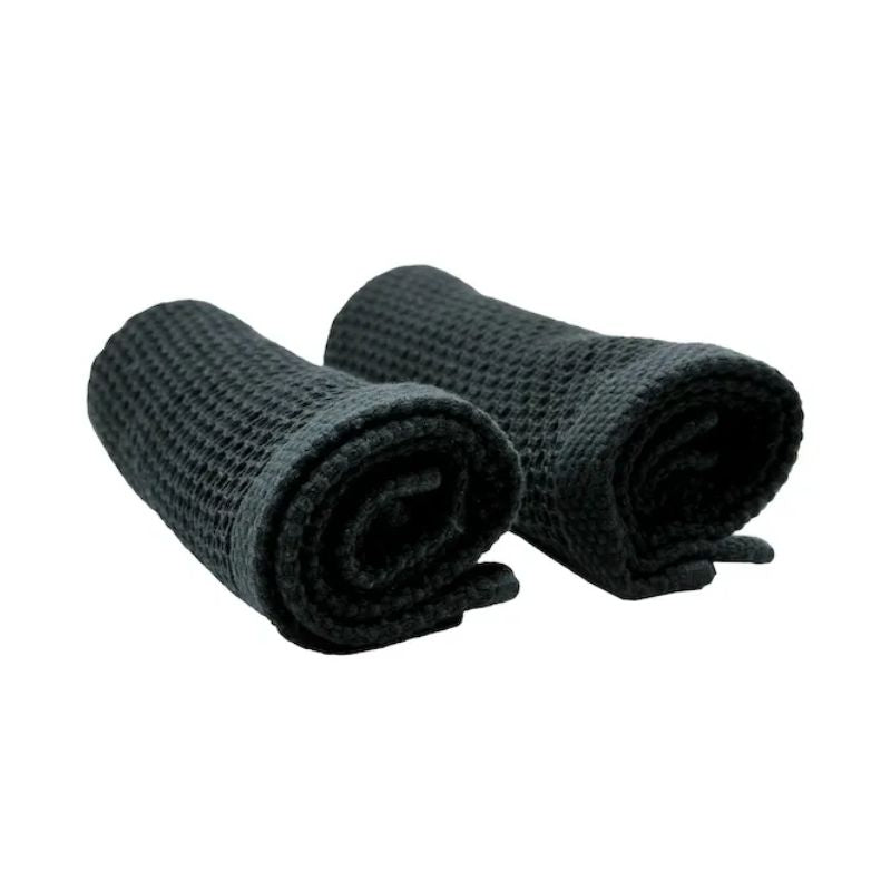 Two rolled black Simple Things cotton wash cloths on a white background.