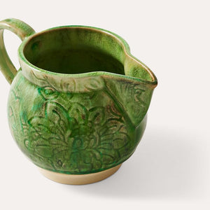 Close up view of the Sthal Arabesque Creamer in Seaweed green showing floral detail in ceramic and crackling from reactive glaze.