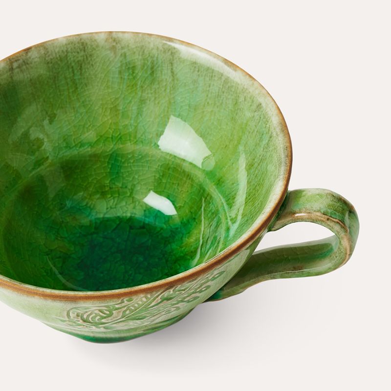 Sthal Arabesque Cup with Handle in the seaweed green colourway, shown against a green background.