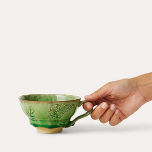 Hand holding the Sthal Arabesque Cup with Handle in Seaweed green shown against a white background.