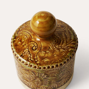 Decorative ceramic mustard yellow tea caddy with intricate floral patterns and a crackled glazed on a white background.