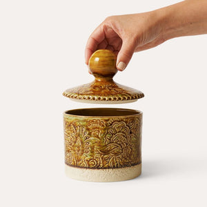 Hand holding the lid on the Pineapple coloured Sthal Arabesque Tea Caddy, shown on a white background.