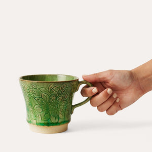 Hand holding the Sthal Arabesque Tea Mug in Seaweed shown on a white background.