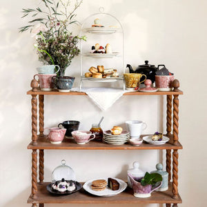 Wooden shelving unit with various ceramic items from the Sthal Arabesque range and food on a white wall background.