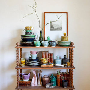 Wooden shelf with ceramic plates, mugs, tea caddies, creamers and jugs from the Sthal Arabesque range.
