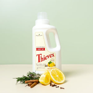 Young Living Thieves Laundry Soap with lemons, cloves, cinnamon sticks and rosemary on a green background