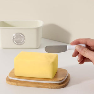 Typhoon Living Butter Dish in Cream shown in use with a block of butter on the bamboo lid.