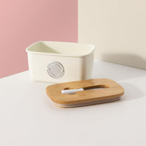 Typhoon Living Butter Dish in Cream shown side on against a pink background with the lid off.