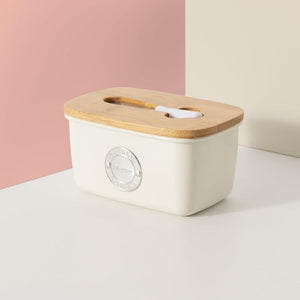 Typhoon Living Butter Dish in Cream shown side on against a pink background.