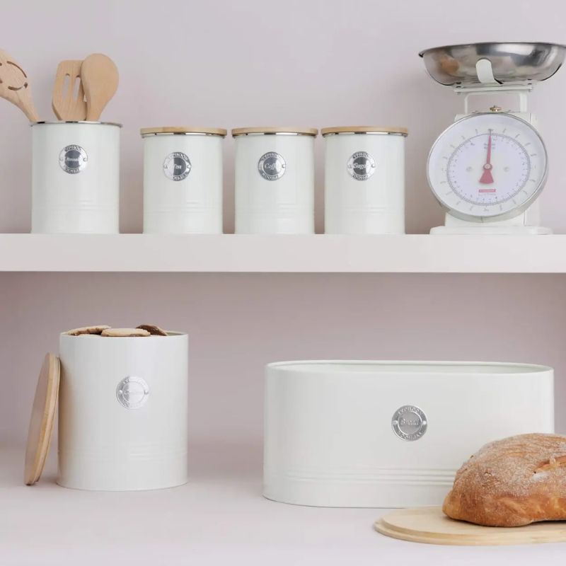 Cream Typhoon Living collection item in a kitchen - tea, coffee, and sugar canisters, utensil holder, scales, cookie storage canisters, and bread bin.