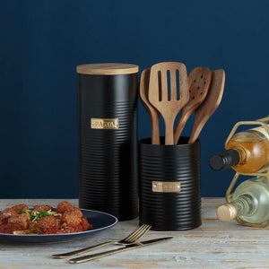 Styled kitchen scene featuring Typhoon Otto black ribbed utensil holder with wooden cooking utensils and pasta canister.