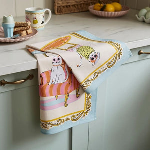 Ulster Weavers Cool Cats Cotton Tea Towel hanging on a green kitchen cabinet handle