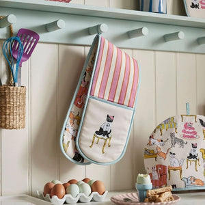 Ulster Weavers Cool Cats Double Oven Glove hung up on a blue hook styled next to eggs and a tea cozy.