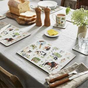 A styled dining table setting featuring the Ulster Weavers Portman Farm Placemats alongside bread, a mug, butter, a glass of water, and cutlery on a light gray tablecloth.