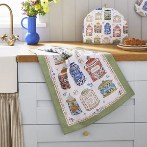 Kitchen scene with the Ulster Weavers Tea Tins Cotton Tea Towel draped on a wooden countertop.