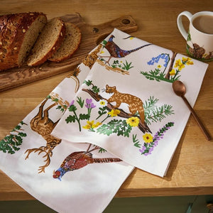 Ulster Weavers Thistlewood Cotton Tea Towel on a wooden table with bread and a mug.