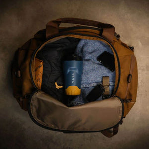 VSSL Rift Tumbler in Pacific Blue styled in a brown duffel bag is shown open from a top-down view.