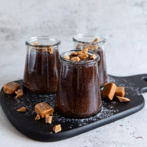 Weck Trapezoid Glass Jars in 280 mL filled with a chocolate and caramel dessert on a black board.