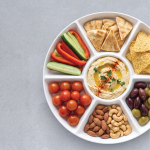Wilkie Brothers White Round Divided Serving Platter filled with nibbles on a grey surface.